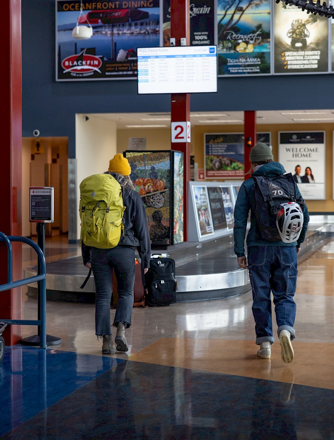 Two people at a luggage carousel at Comox Airport