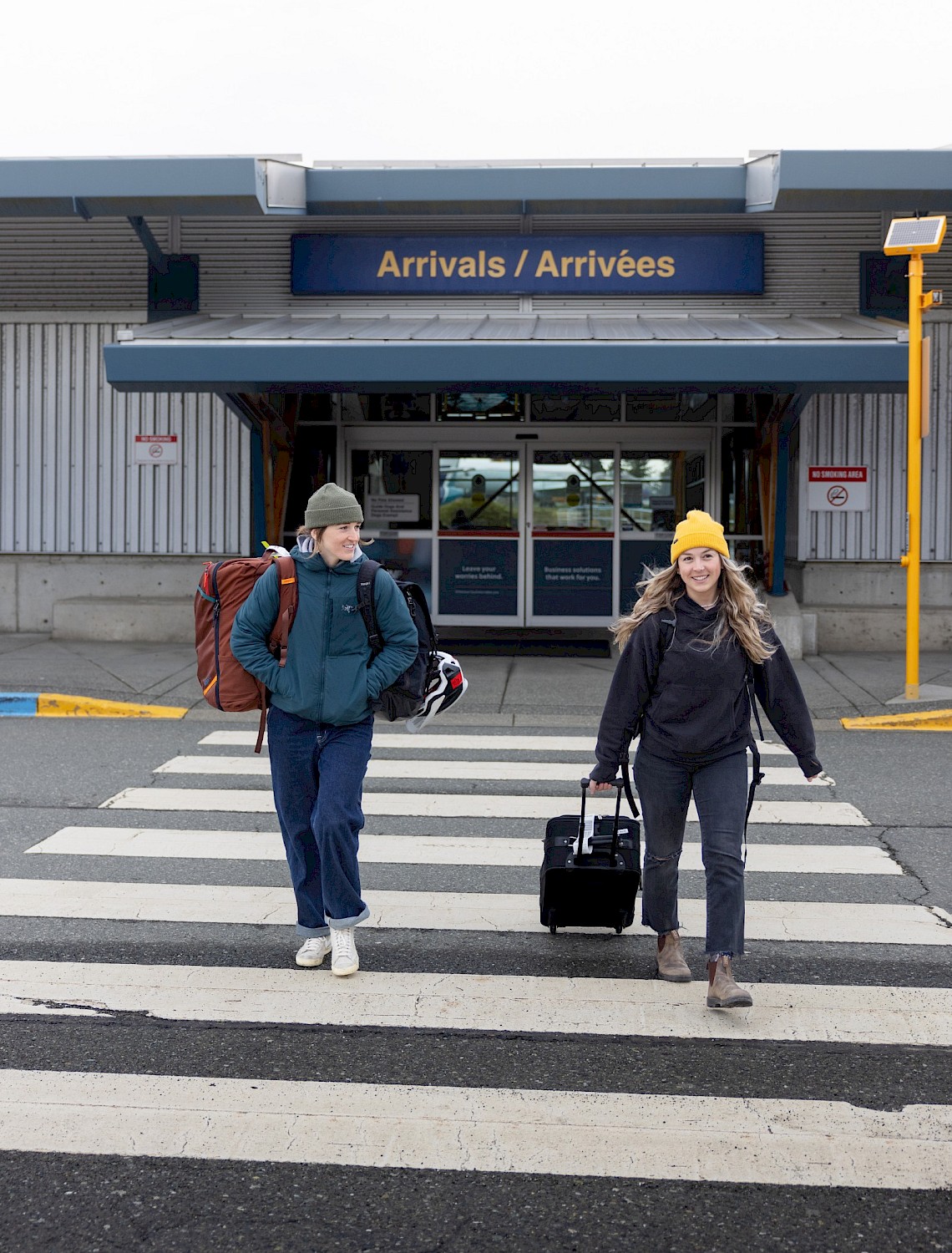 Two people on a crosswalk at the arrivals terminal at Comox Airport
