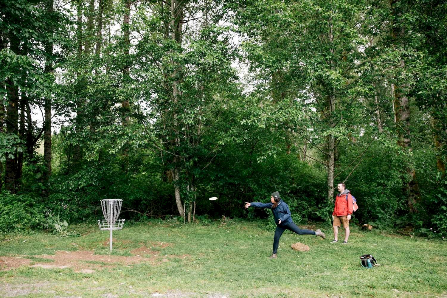 Woman throwing a disc playing disc golf